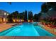 Beautiful pool with custom stonework, lush greenery, and elegant lighting for a relaxing backyard retreat at 7033 Twin Forks Peak St, Las Vegas, NV 89166