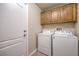 A convenient laundry room features a washer, dryer, and upper wood cabinets at 7998 Base Camp Ave, Las Vegas, NV 89178
