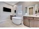 Luxurious bathroom with a standalone soaking tub and -and- vanities with modern finishes at 8934 Windgate Ranch St, Las Vegas, NV 89166