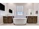 Well-lit bathroom with a modern standalone tub, separate vanities, and sleek glass shower at 8934 Windgate Ranch St, Las Vegas, NV 89166