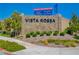 Stone sign for Vista Rossa at Skye Canyon featuring attractive landscaping and a banner for sales event at 8934 Windgate Ranch St, Las Vegas, NV 89166