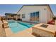 A backyard pool with a tanning ledge, integrated spa, a custom built-in outdoor kitchen, and backyard access at 8934 Windgate Ranch St, Las Vegas, NV 89166