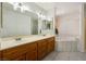 Bright bathroom featuring double sinks, wood cabinetry, large mirror, and tiled floors and tub at 901 E Jaybird St, Pahrump, NV 89048