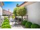 Charming courtyard entrance featuring a wrought iron gate, lush greenery, and inviting landscape design at 9704 Brawley Dr, Las Vegas, NV 89134