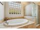 Bright bathroom showcasing a soaking tub under a glass block window and a glass-enclosed shower at 10381 Borah Park Cir, Las Vegas, NV 89178