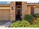 Inviting entrance featuring a stone archway, dark wood door, and well-maintained front yard landscaping at 10381 Borah Park Cir, Las Vegas, NV 89178