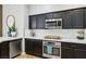 Modern kitchen features dark cabinets, quartz countertops, stainless steel appliances and tile flooring at 10381 Borah Park Cir, Las Vegas, NV 89178