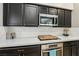 Kitchen featuring dark cabinets, quartz countertops, stainless steel appliances and tile backsplash at 10381 Borah Park Cir, Las Vegas, NV 89178