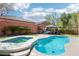 Lush backyard with a freeform pool, spa with waterfall feature, patio, and green grass at 10381 Borah Park Cir, Las Vegas, NV 89178