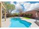 Inviting backyard oasis with a sparkling blue pool, spa, lush landscaping, and string lights at 10381 Borah Park Cir, Las Vegas, NV 89178
