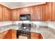 Cozy kitchen with wood cabinets, granite countertops and black appliances at 105 Lighthouse Dr # 105, Boulder City, NV 89005
