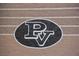 Close-up of the Palo Verde High School 'PV' logo on a textured brick wall at 11016 Meadow Leaf Ave, Las Vegas, NV 89144