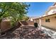 Large backyard with mature tree, gravel, covered patio, and brick wall at 11147 Verismo St, Las Vegas, NV 89141