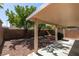 Spacious backyard with gravel, mature trees, covered patio, and brick perimeter wall at 11147 Verismo St, Las Vegas, NV 89141