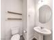Compact powder room featuring a pedestal sink, round mirror, wood shelving, and a toilet at 1197 Mission View Ct, Henderson, NV 89002