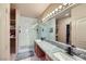 Modern bathroom featuring double sinks, granite countertops, and a glass-enclosed shower with marble tile at 2325 Windmill Pkwy # 1622, Henderson, NV 89074