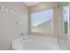 Bright bathroom features a full size bathtub with a glass shower and a view from a window at 249 Cinnamon Ridge Way, Henderson, NV 89015