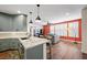 Open kitchen flowing to living area, featuring gray cabinets, granite counters, stainless appliances, and wood floors at 249 Cinnamon Ridge Way, Henderson, NV 89015