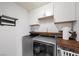 Laundry room with a washer, dryer, and white cabinets. Includes a wooden shelf at 249 Cinnamon Ridge Way, Henderson, NV 89015