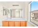 Bright bathroom featuring a single sink vanity, large mirror, and a view from the window at 2558 Lazy Saddle Dr, Henderson, NV 89002