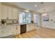Bright kitchen with granite countertops, a stainless steel dishwasher, white cabinets, and an adjacent dining area at 4963 Crooked Stick Way, Las Vegas, NV 89113