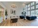 Bright living room with a dining area, fireplace, tall windows, and blue velvet sofas overlooking a lush outdoor view at 4963 Crooked Stick Way, Las Vegas, NV 89113