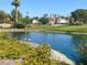 Scenic pond featuring flowering plants, green landscaping, and a serene golf course view at 4963 Crooked Stick Way, Las Vegas, NV 89113