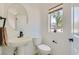 Powder room featuring a pedestal sink, round mirror, and window with natural light at 5804 Gossamer Stone Ct, Las Vegas, NV 89141