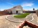 Large backyard featuring synthetic grass, desert landscaping, and a covered patio at 6696 Merced Lake Dr, Las Vegas, NV 89156