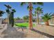 Landscaped backyard featuring a synthetic grass area and desert landscaping with mature palm trees at 6971 Moaning Cavern St, Las Vegas, NV 89131