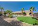 Expansive backyard featuring a pool, covered patio, desert landscaping, and mature palm trees at 6971 Moaning Cavern St, Las Vegas, NV 89131