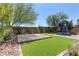 Landscaped backyard featuring artificial grass, paving stones, and trees for shade at 7705 Alder Forest St, Las Vegas, NV 89113