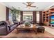 Cozy living room with leather sofas, decorative ceiling fan, and backyard views at 8623 Kennedy Heights Ct, Las Vegas, NV 89131
