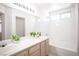Bathroom featuring double sinks, a large mirror, white cabinets, and a shower-tub combo with white tiles at 9728 Drumcannon Ave, Las Vegas, NV 89129