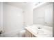 A bathroom featuring a tub with white tiles, white toilet and a sink with a mirror and light at 9728 Drumcannon Ave, Las Vegas, NV 89129