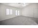A spacious bedroom with gray carpet, white walls, a ceiling fan, and a view to the exterior at 9728 Drumcannon Ave, Las Vegas, NV 89129
