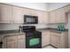A kitchen featuring wooden cabinets, granite countertops, and black appliances including a microwave and oven at 9728 Drumcannon Ave, Las Vegas, NV 89129