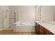 Elegant bathroom with separate shower, soaking tub, and wood vanity at 10348 Hawks Wing St, Las Vegas, NV 89178