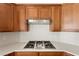 Modern kitchen featuring granite countertops, wooden cabinets, and a stainless steel cooktop with hood at 10348 Hawks Wing St, Las Vegas, NV 89178