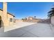 Wide backyard view with a large concrete area, block fence, and mature trees at 1708 Anzio St, Las Vegas, NV 89108