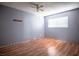A minimal bedroom features light gray walls and wood-look floors with a ceiling fan and window at 2721 Merritt Ave, Las Vegas, NV 89102