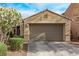 Exterior view featuring a tan colored two-car garage and adjacent landscaping at 3005 Dotted Wren Ave, North Las Vegas, NV 89084