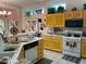 Well-lit kitchen with charming yellow cabinetry, tile flooring, white appliances, and multiple windows at 3028 Ripon Dr, Las Vegas, NV 89134