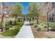 An inviting walkway leads to townhomes, complemented by lush trees and landscaped gardens on a bright sunny day at 3358 Via Strada St, Henderson, NV 89044