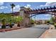 Community entrance with stone accents, lush landscaping, and palm trees under a bright, cloudy sky at 4990 River Glen Dr # 171, Las Vegas, NV 89103