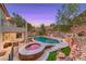 A luxurious backyard with a sparkling pool and spa are surrounded by lush landscaping and scenic views at 53 Precipice Ct, Henderson, NV 89002