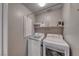 Functional laundry room with a washer, dryer, storage shelf, and ironing board for convenience at 53 Precipice Ct, Henderson, NV 89002
