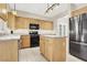 Well-lit kitchen with stainless steel refrigerator, kitchen island and light wood cabinets at 636 Pacific Cascades Dr, Henderson, NV 89012