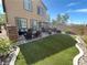 A backyard with a stone fireplace, a patio with dining set, and a well-maintained lawn at 6682 Salt Pond Bay St, Las Vegas, NV 89149