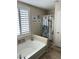 Bright bathroom featuring a soaking tub, tiled floors, and a tropical shower curtain at 6682 Salt Pond Bay St, Las Vegas, NV 89149